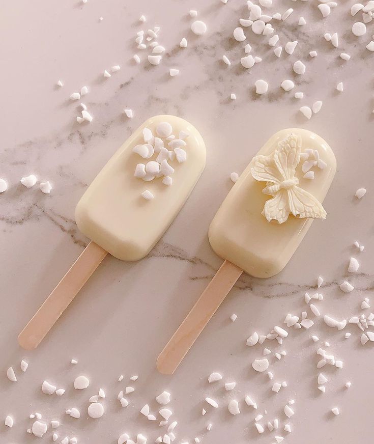 two pops with flowers on them sitting next to some scattered white sugar and sprinkles