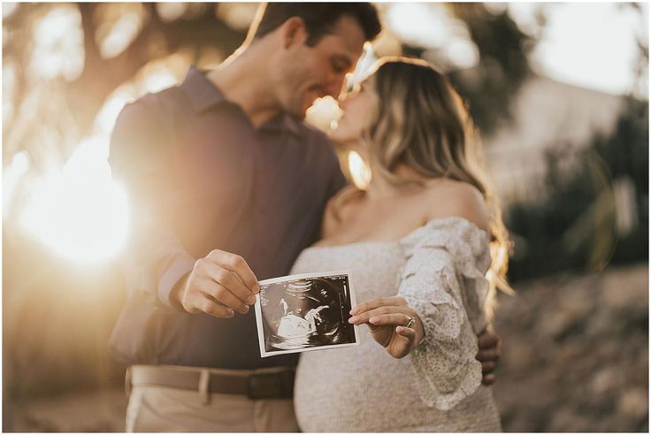 a man and woman standing next to each other while holding up an old fashioned photo