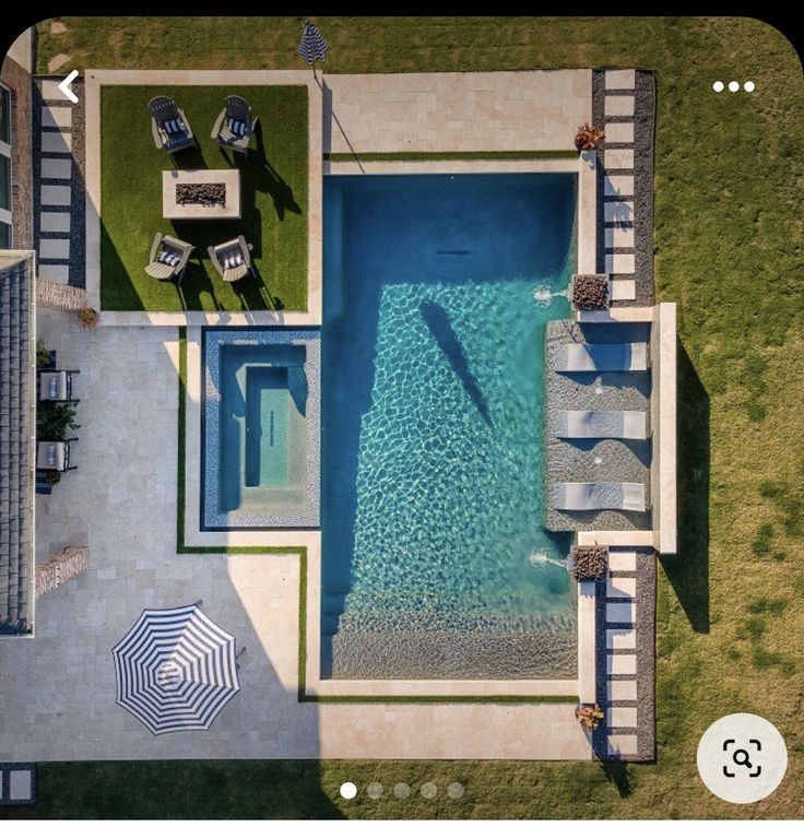 an aerial view of a pool and patio with umbrellas in the grass next to it