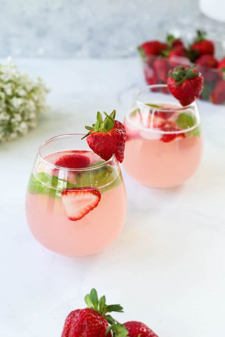 two glasses filled with ice and strawberries on a tray