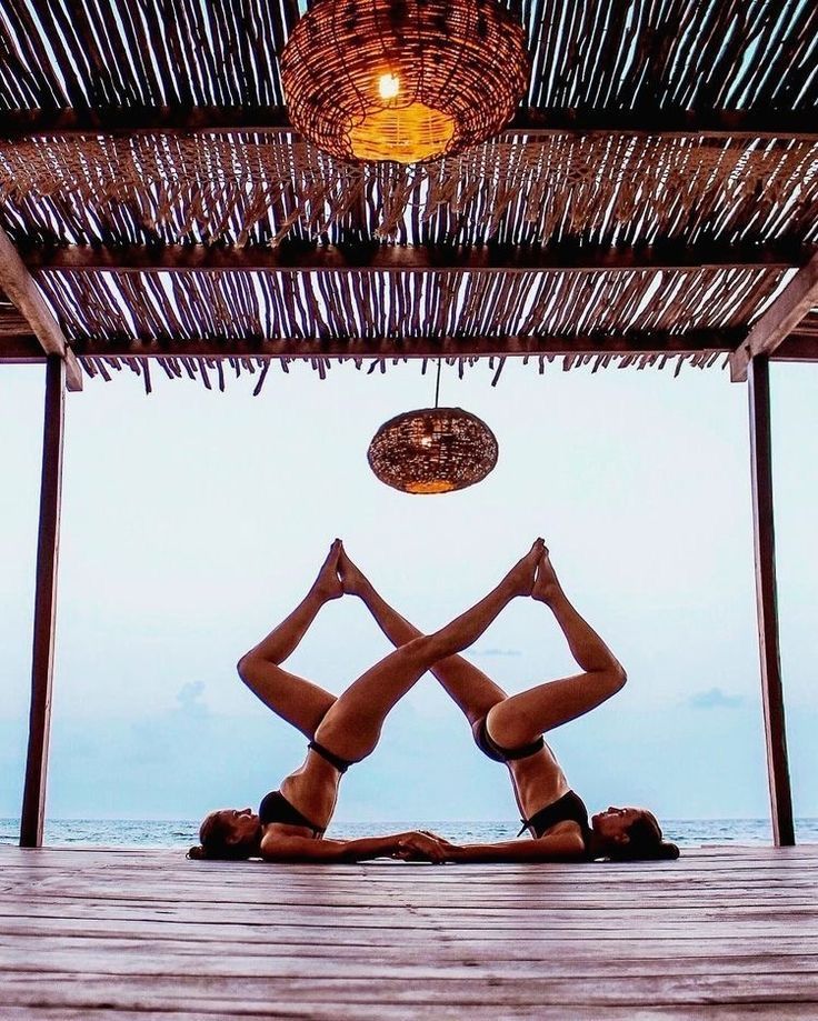 two women are doing yoga in front of the ocean