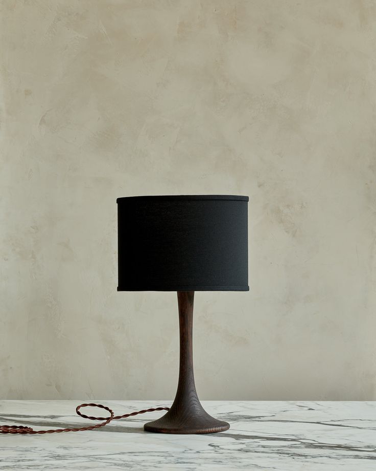 a table lamp with a black shade on it and a red cord hanging from the base