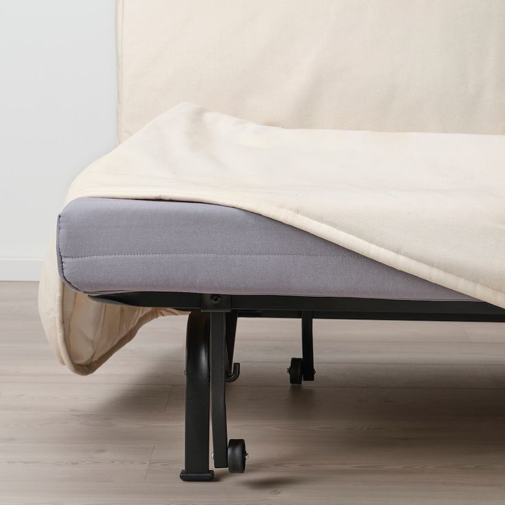 a bed with a white sheet on top of it and black wheels underneath the mattress