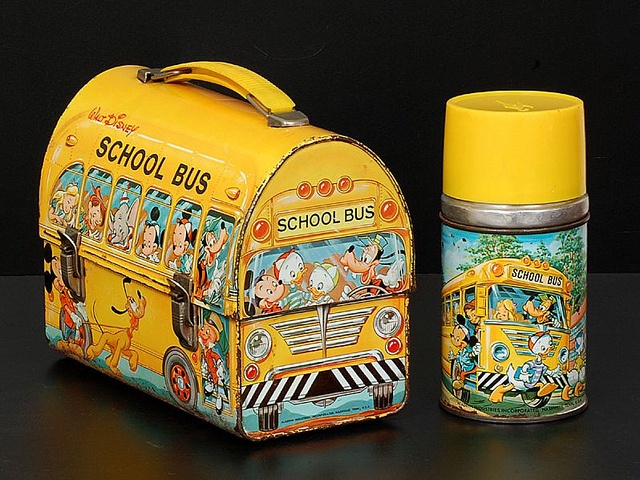 a yellow school bus shaped lunch box next to a canister