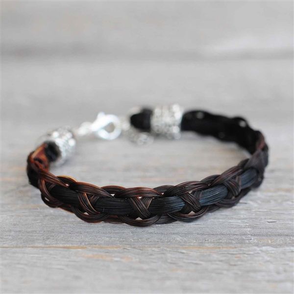 a black and brown braided bracelet on a wooden table