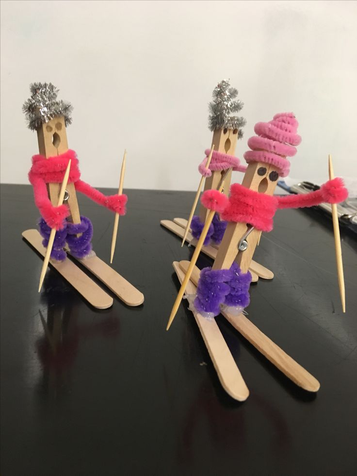 three popsicle puppets are dressed in pink, purple and silver hats with sticks sticking out of them