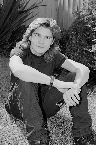 a black and white photo of a woman sitting in the grass with her hands on her knees