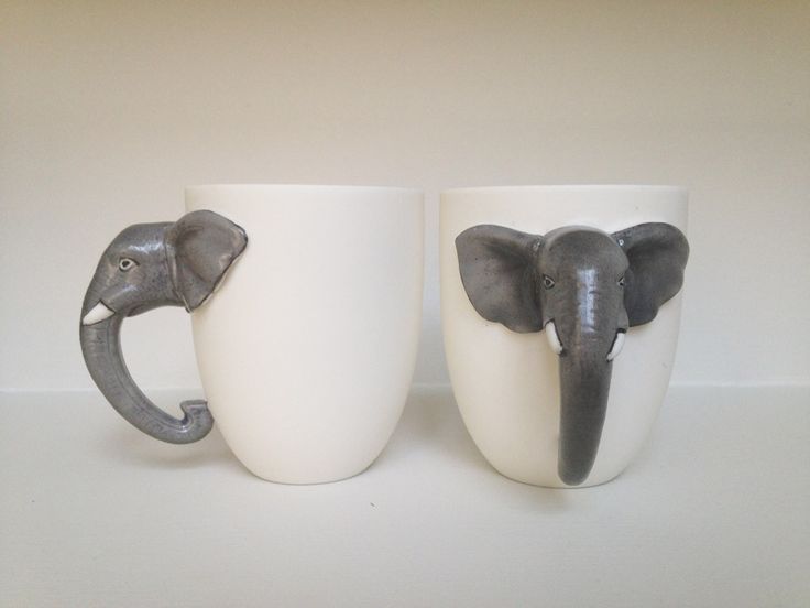 two coffee mugs with elephants on them sitting next to each other in front of a white wall