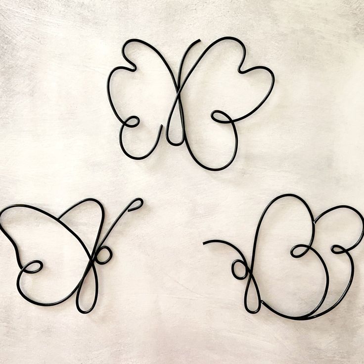 three metal butterfly sculptures sitting on top of a white wall