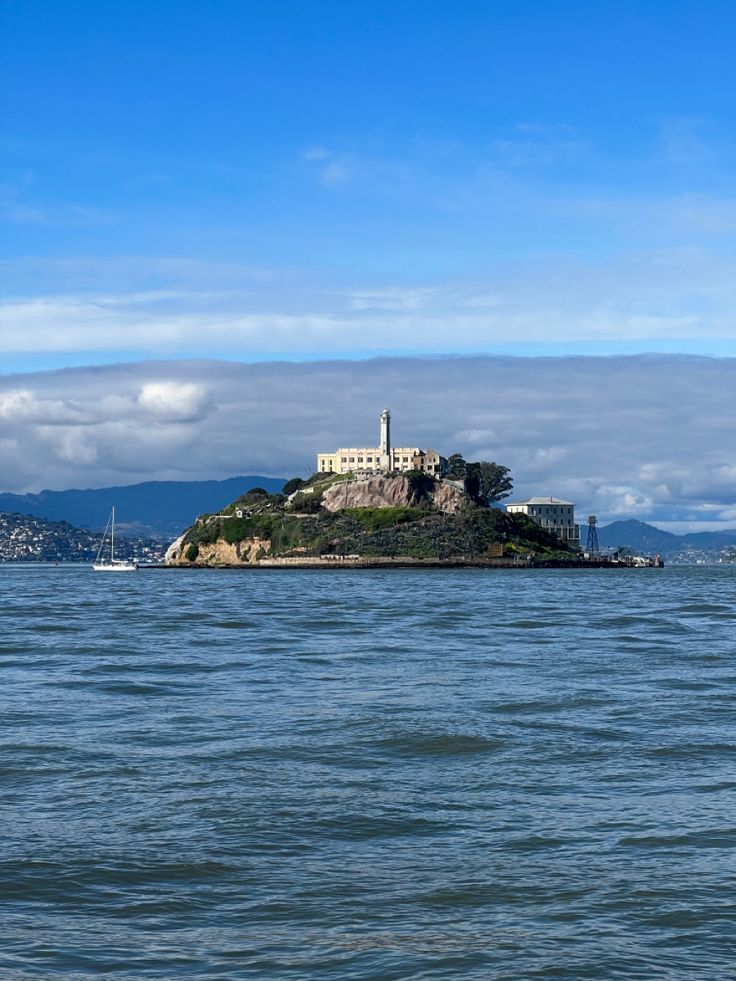 an island in the middle of water with a lighthouse on it