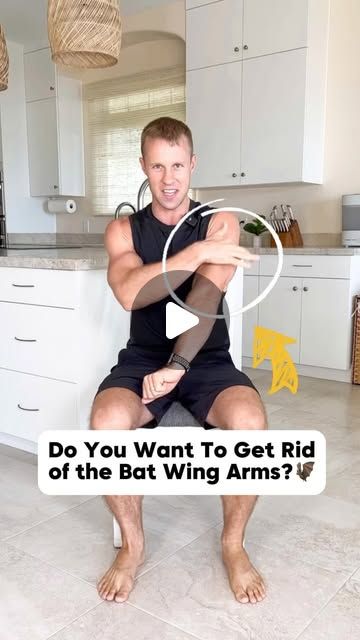 a man sitting on top of a kitchen floor next to a counter with an arm in the air