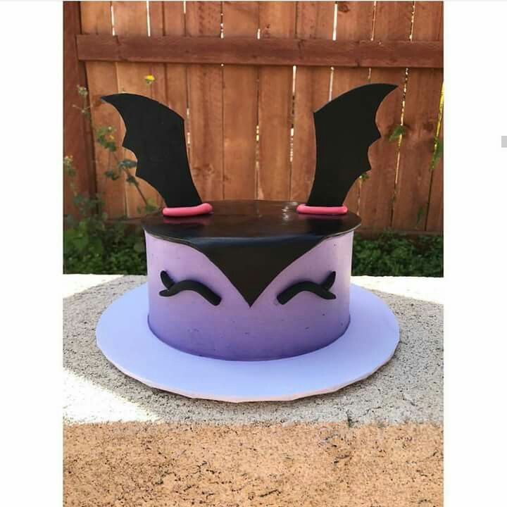 a purple cake with black icing and a bat decoration on it's top