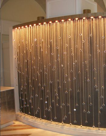 a shower curtain with beads hanging from it's side and lights on the wall