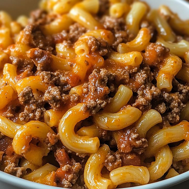 a close up of a bowl of pasta with meat and cheese on the top, ready to be eaten