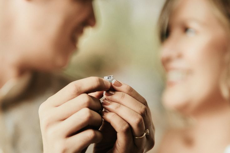 a man and woman are holding hands with each other while they look at the ring on their finger