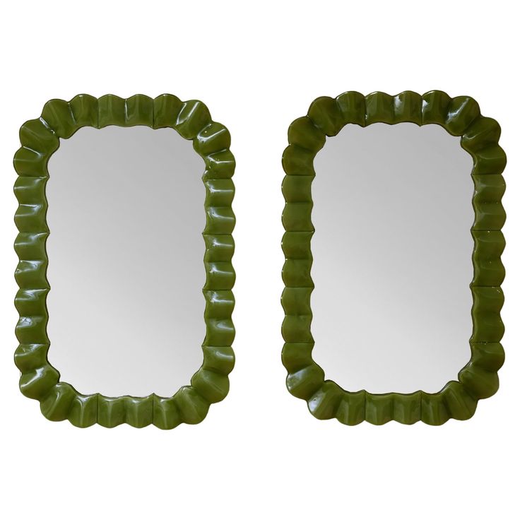 a pair of green scalloped mirrors sitting next to each other