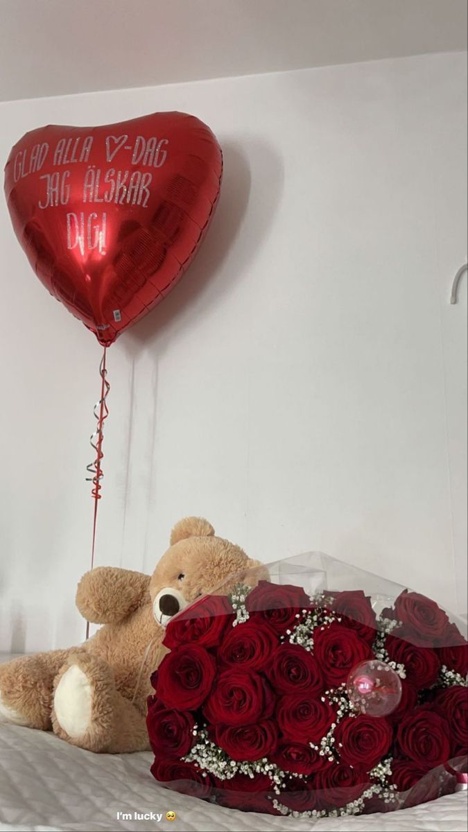 a teddy bear sitting next to a bouquet of roses and a heart - shaped balloon