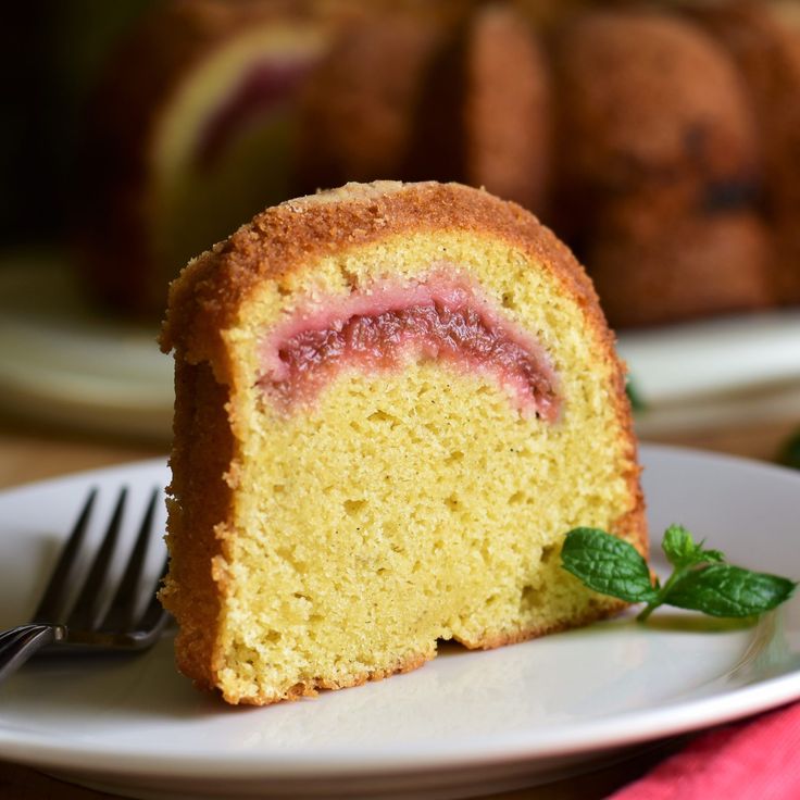 a piece of cake on a white plate with a fork next to it and another slice in the background