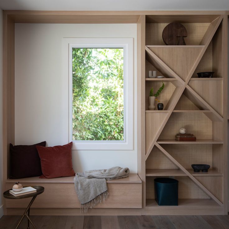 a window seat in the corner of a room with bookshelves and pillows on it