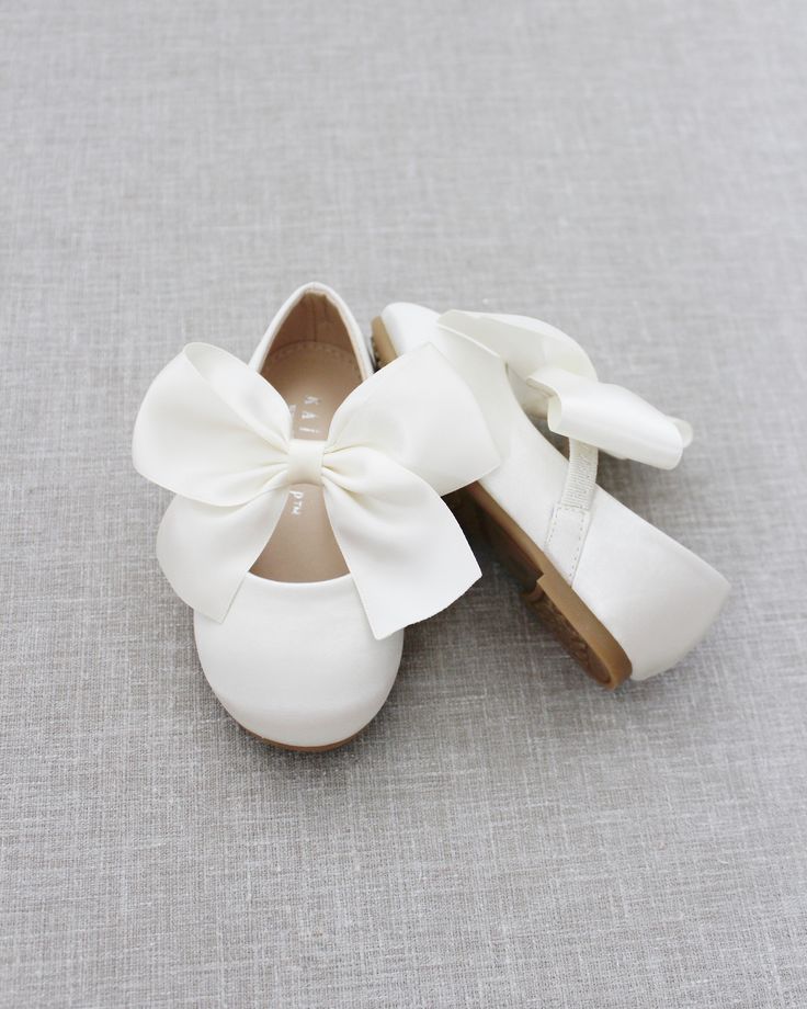 two pairs of white shoes with a large bow on the front and back of them