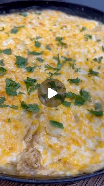 a pan filled with cheese and greens on top of a wooden table next to a knife