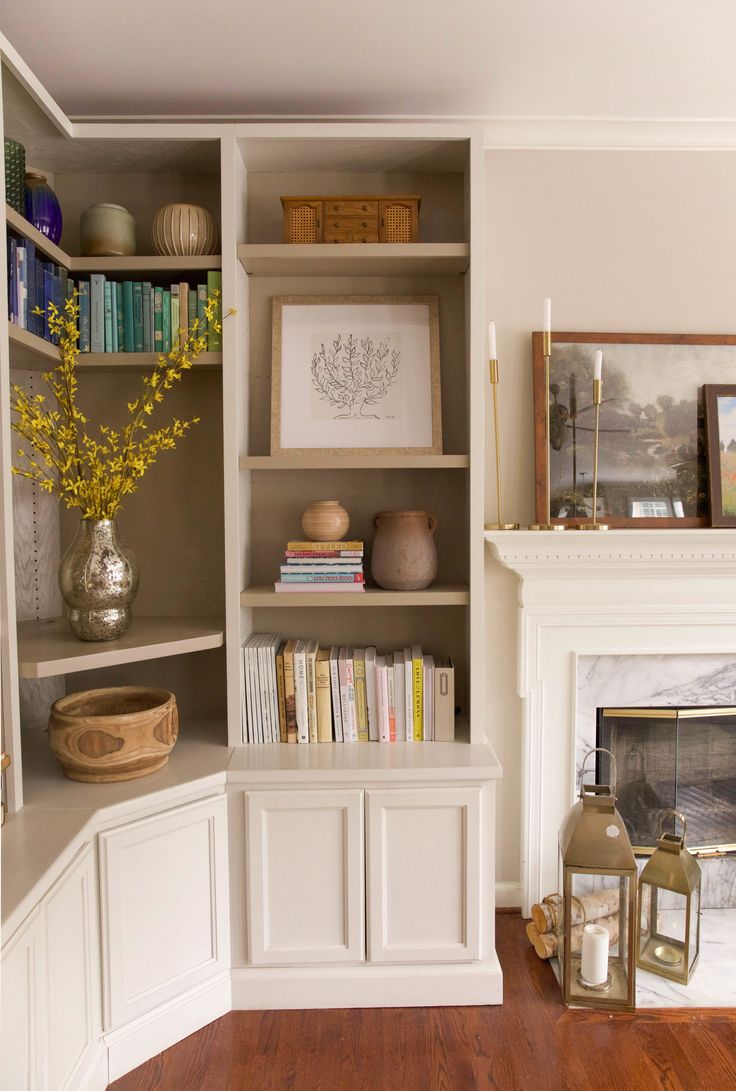 a living room with bookshelves, fireplace and pictures on the wall in it