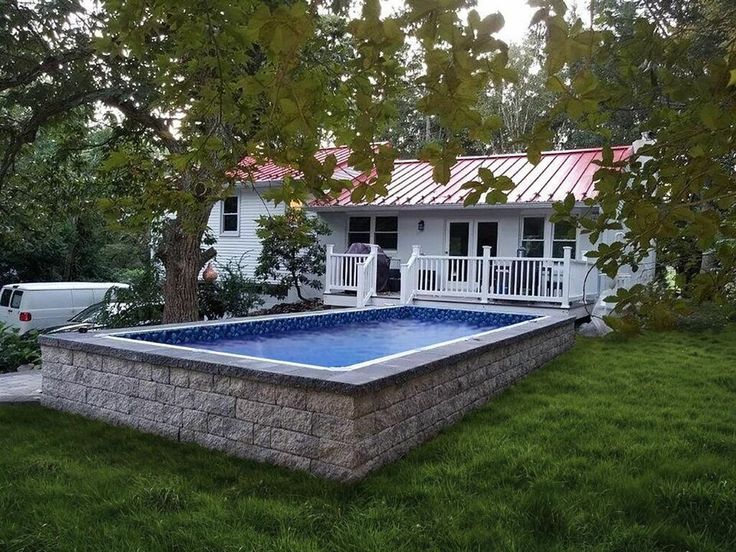 an above ground pool surrounded by lush green grass with a white house in the background