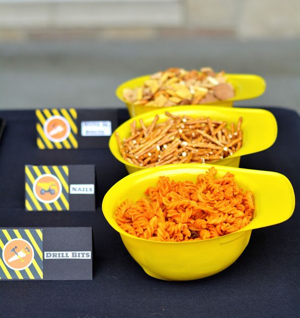 three yellow bowls filled with food sitting on top of a black table covered in paper