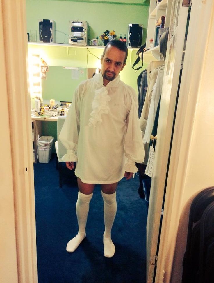 a man standing in front of a mirror wearing white socks and a shirt with ruffles on it