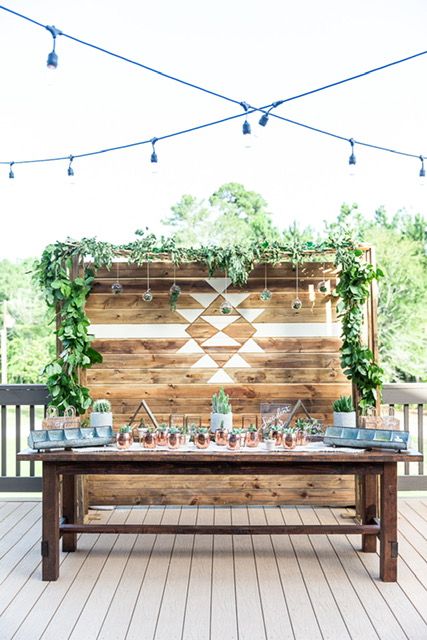 an outdoor table with candles and greenery on it