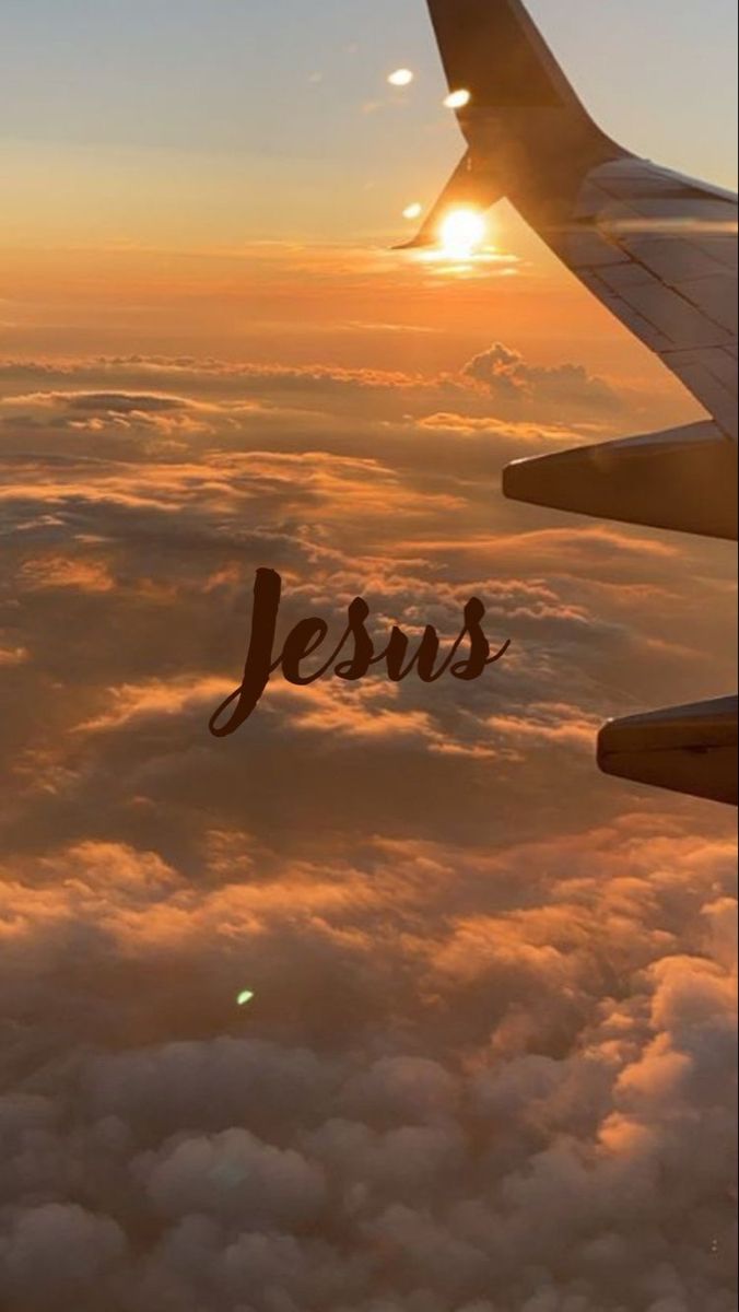 an airplane wing with the word jesus written on it in front of clouds at sunset