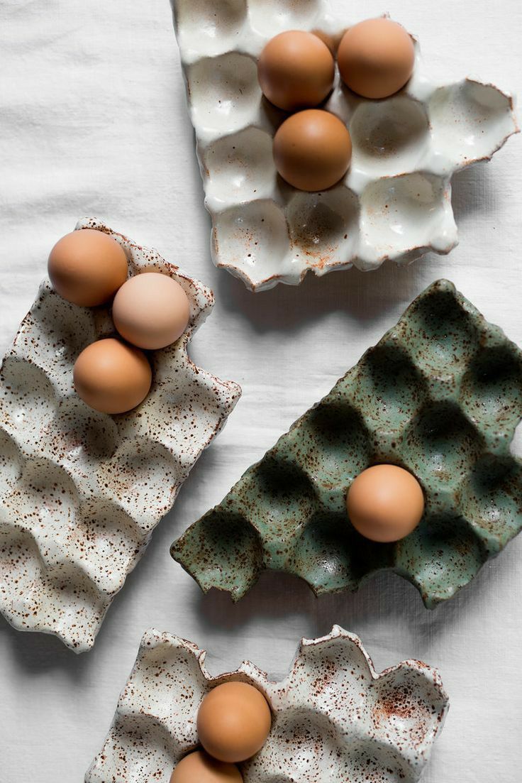 three eggs in an egg carton on a white tablecloth next to one another