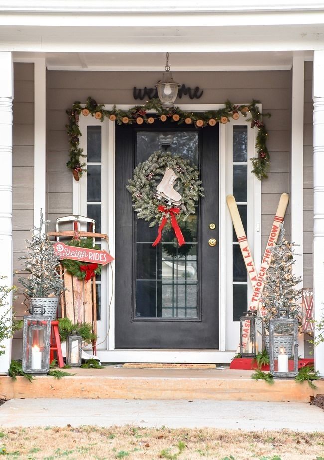 a front porch decorated for christmas with wreaths and baseball bats on the door sill