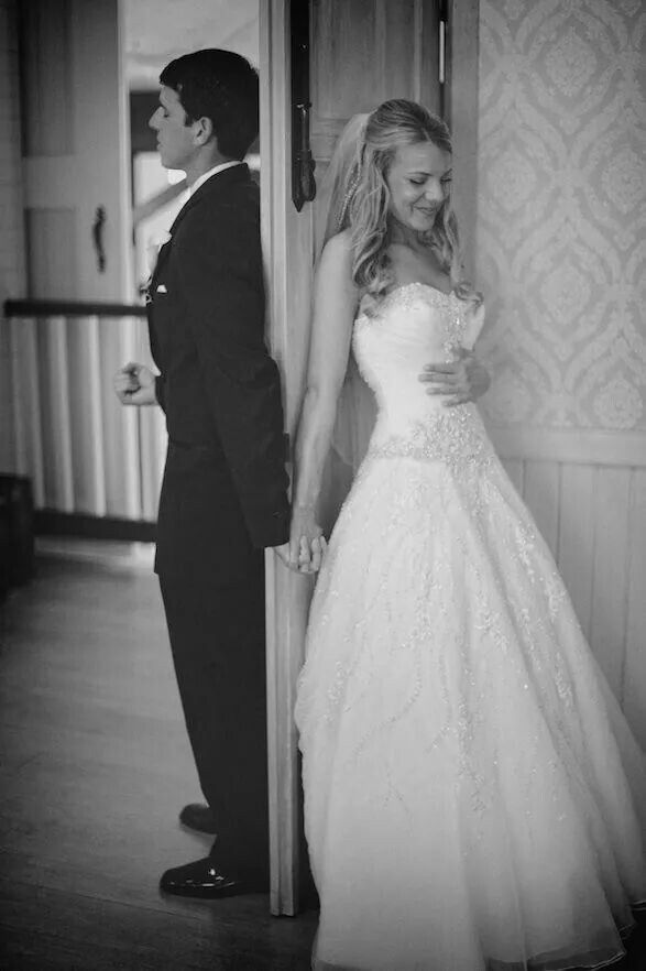 a man and woman standing next to each other in front of a door wearing wedding dresses