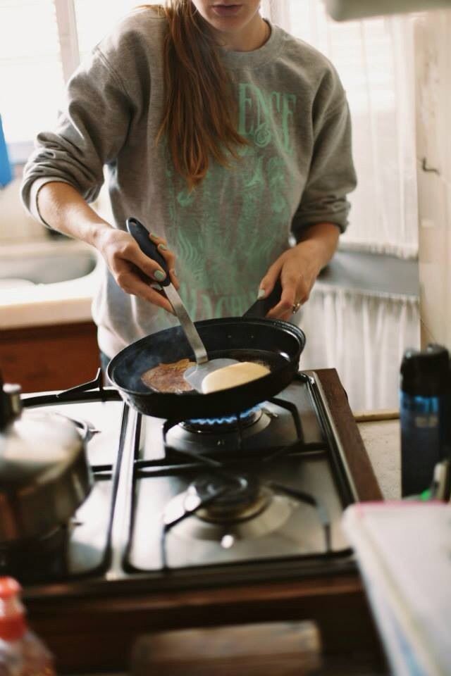 a woman cooking food on top of a stove with a spatula in her hand