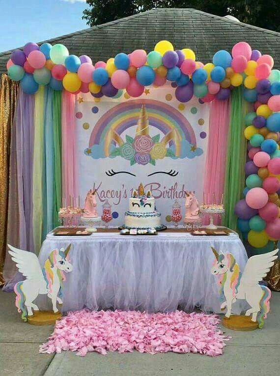 a unicorn themed birthday party with balloons, streamers and table cloths on the ground