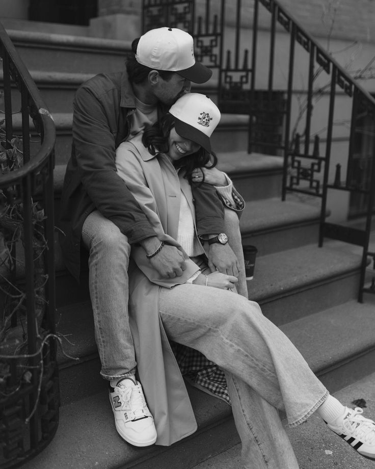 a man and woman sitting on the steps with their arms around each other as they kiss