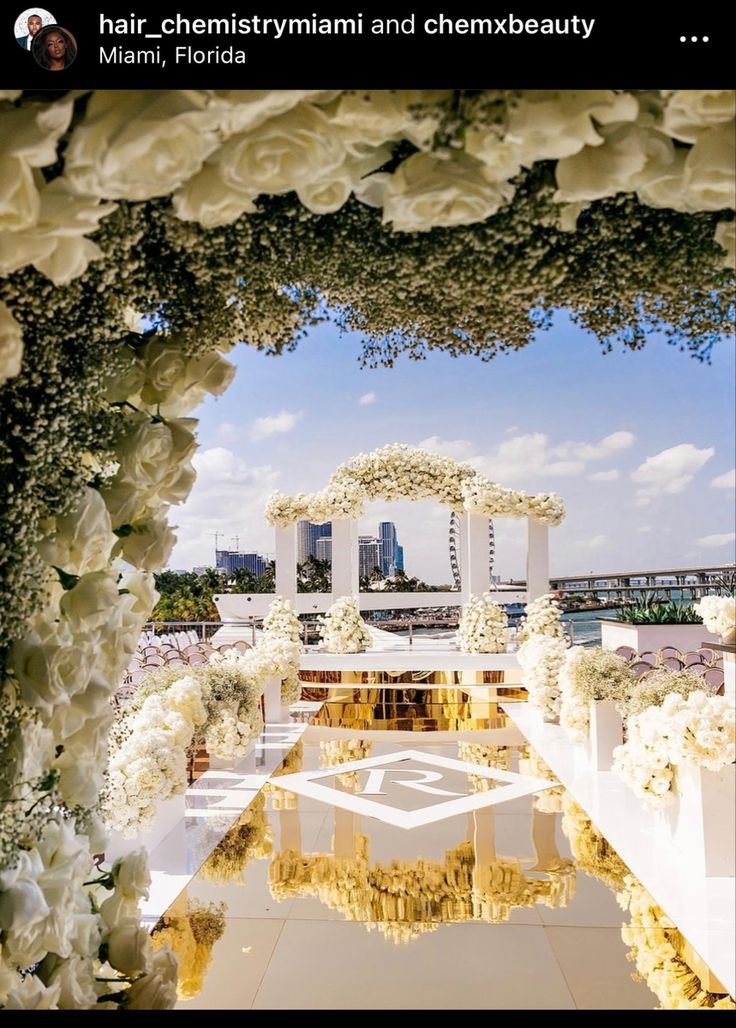 an outdoor ceremony setup with white flowers and greenery on the ground, in front of a cityscape