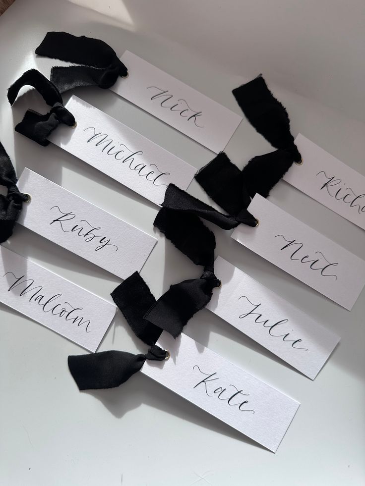 four name tags with black satin ribbons on white table cloth, one for the bride and one for the groom