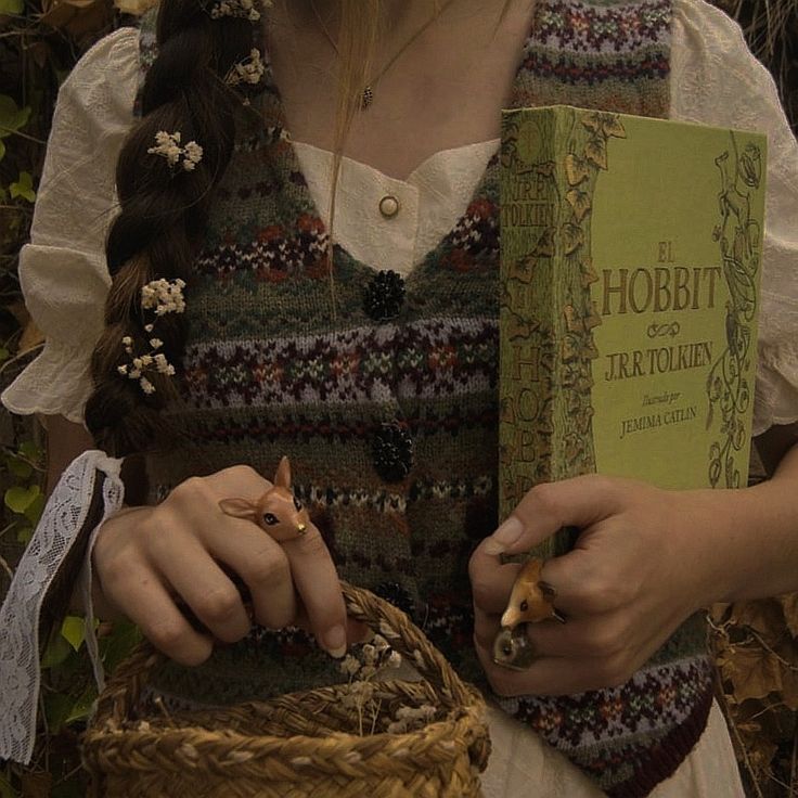 a woman is holding a book in her hands and wearing a straw basket with an animal on it