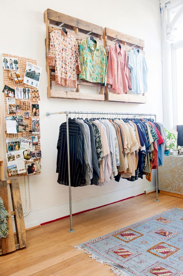 a clothing rack with clothes hanging on it in a room next to a couch and window