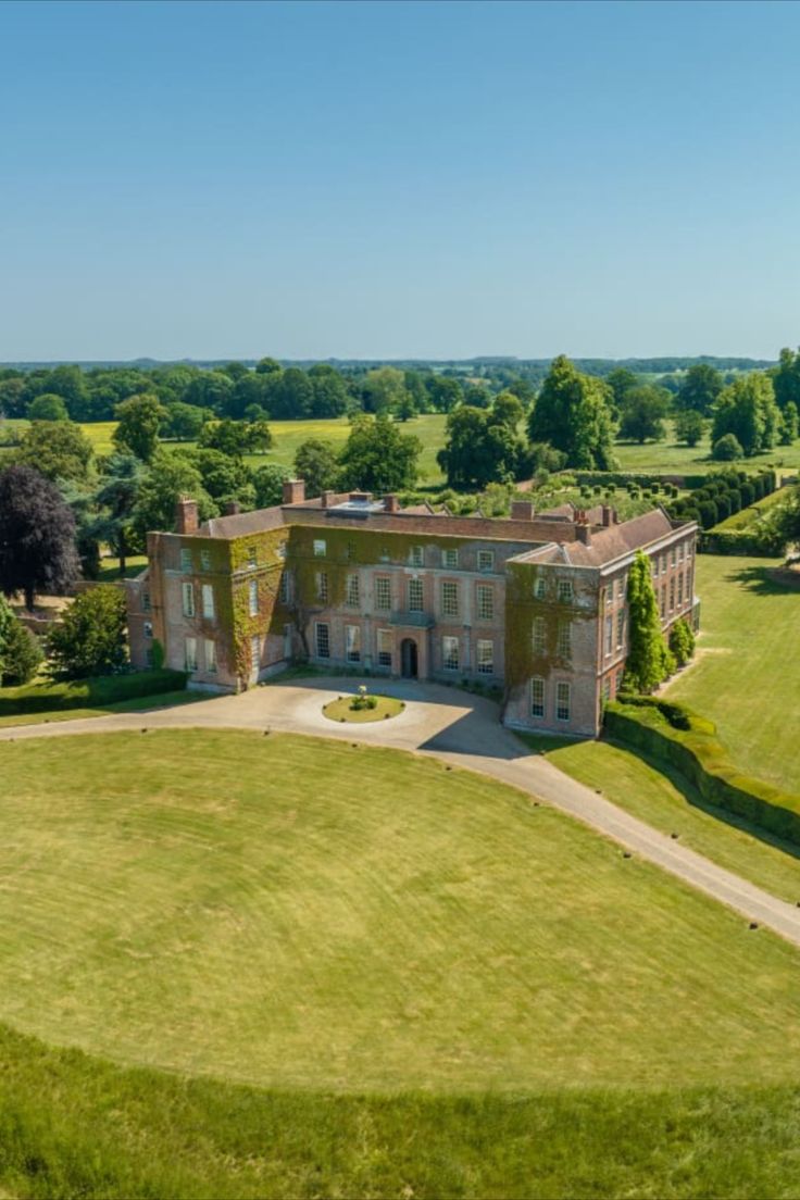 an aerial view of a large building in the middle of a green field