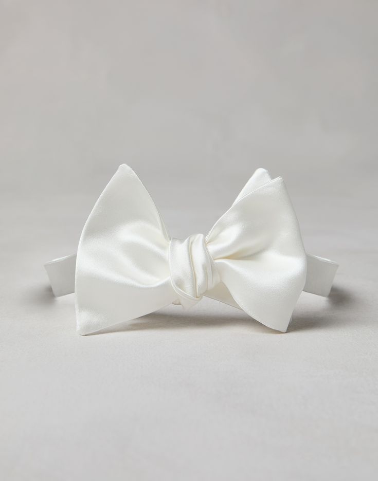 Cotton and silk satin bow tie An essential accessory for evening events, the cotton and silk satin bow tie completes tuxedos with classic flair. This accessory, which must be tied, is adjustable thanks to a convenient hook-and-loop closure behind the neck. Pre-tied Satin Bow For Black Tie Events, Elegant White Suit And Tie Accessories For Party, Classic White Bow Tie For Wedding, Elegant White Bow Tie For Black Tie Occasions, Classic Pre-tied Satin Bow Tie, Classic White Bow For Formal Occasions, Classic White Bow For Black Tie Occasions, White Bow Tie For Black-tie Events, Elegant White Bow Tie For Black-tie Events