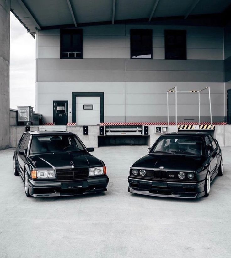 two black cars parked next to each other in front of a building