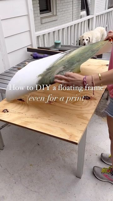 a woman holding a surfboard on top of a wooden table next to a dog