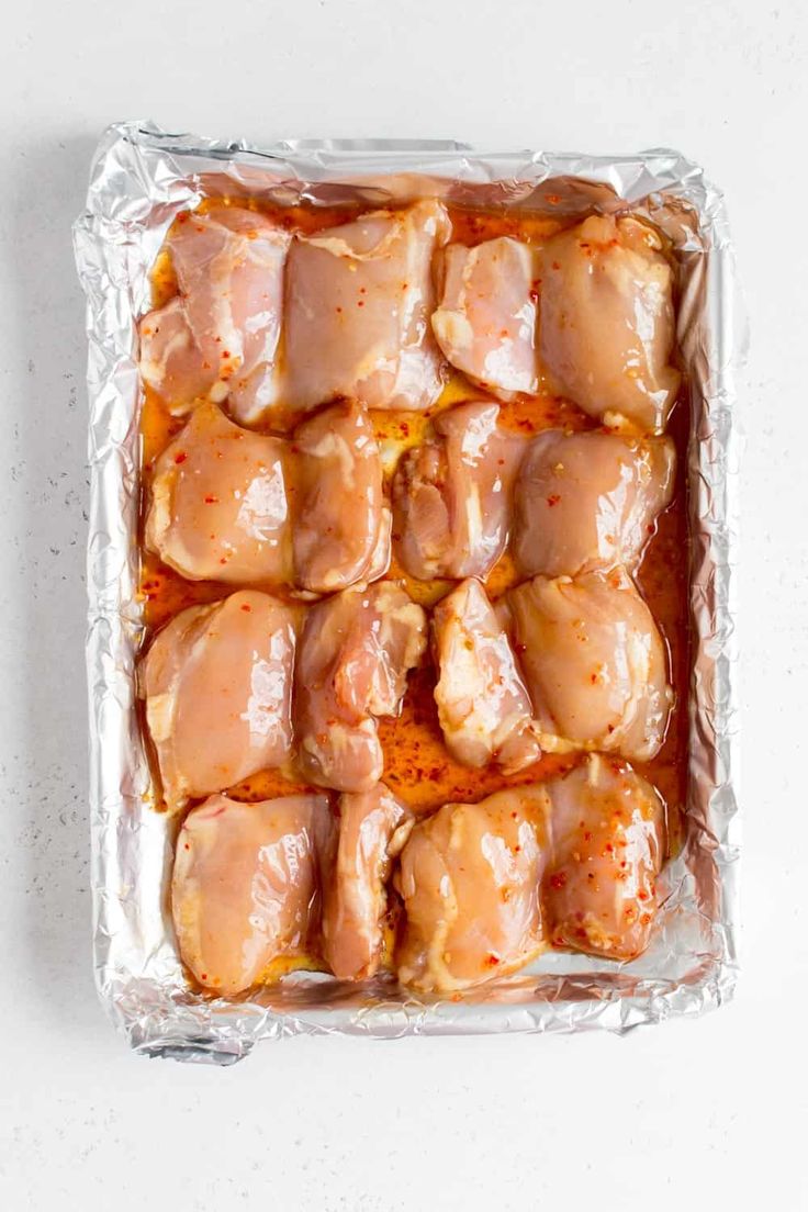 raw chicken wings in tin foil on a white surface