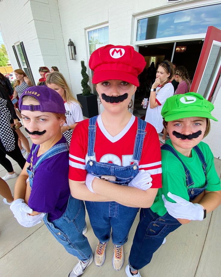 three children with fake mustaches on their faces are standing in front of a building