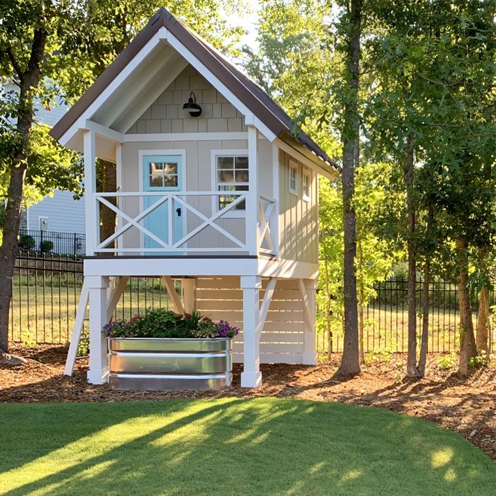 a small white house in the middle of a yard with trees and grass around it