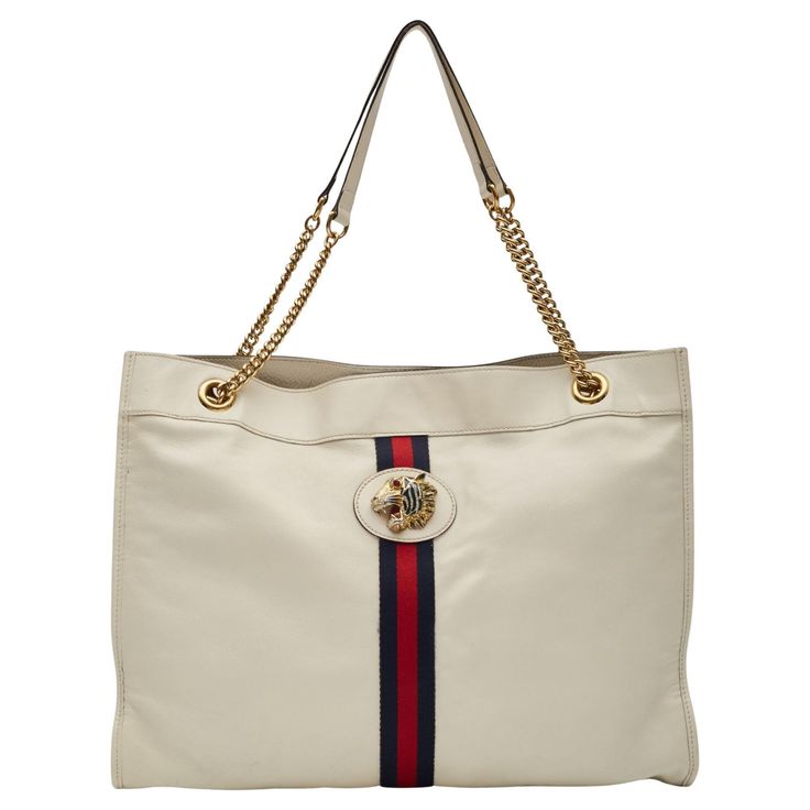 This Gucci tote by Alessandro Michele is constructed of neutrals leather, featuring the signature Sylvie Web accent and Rajah detail. The bag showcases gold-tone hardware, chain-link shoulder straps, crystal tiger head and chain-link accents. The bag is secured with a snap closure at the top and is finished with suede lining with an interior pocket. Vintage Authenticated by entrupy. Color: White with web Material: leather Model No. 537219 Condition: Very good. Faint hairline marks. Bag was refurbished by leather professional. Made in Italy Measurements~ Height 13.75” Width 17.25” Depth 1.75” Drop 10.25” White Gucci Shoulder Bag With Chain Strap, Gucci Leather Lined Shopping Bag, Gucci Tote Bag With Leather Lining, Gucci Leather-lined Shoulder Bag For Shopping, Gucci Leather Lined Tote Bag, Gucci Shoulder Bag With Leather Lining For Shopping, White Leather Gucci Shoulder Bag, Gucci Leather Lined Shoulder Bag For Shopping, Gucci Shoulder Bag With Chain Strap