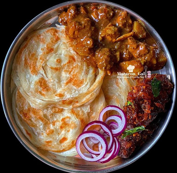 a plate full of food with onions and meats on it, including roti bread